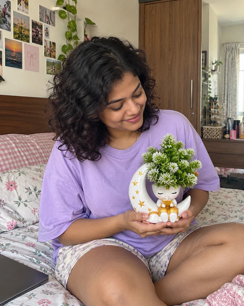 MiniKin Festival Moon Planter with its artificial plant, held on a bed in a cosy bedroom