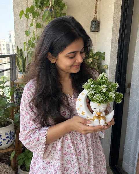 MiniKin Festival Moon Planter with its artificial plant, held by a balcony door