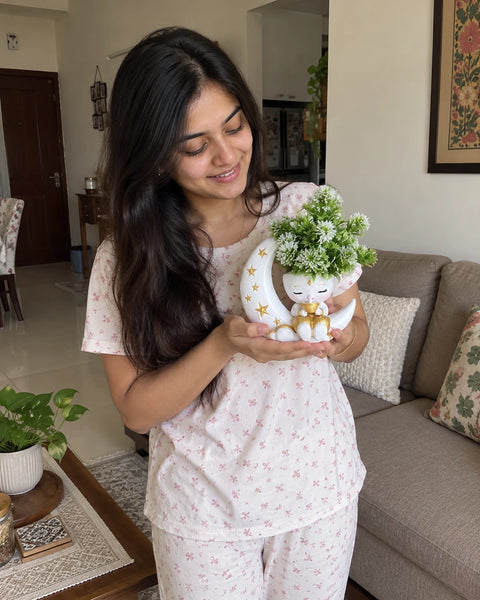 Woman holding the MiniKin Festival Moon Planter with its artificial plant in her living room
