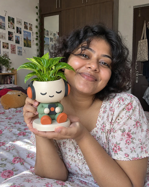 MiniKin Headphone Planter with a plant, held up in a cosy bedroom